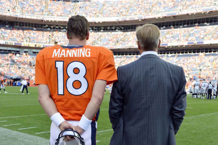 Denver Broncos quarterback Peyton Manning (18) and executive vice president of football operations John Elway talk near the end of the game against the Oakland Raiders at Sports Authority Field. The Broncos defeated the Raiders 37-6.