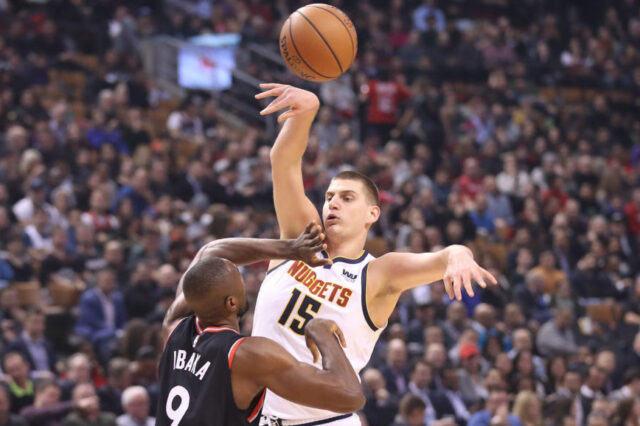 Denver Nuggets center Nikola Jokic (15) passes the ball under defensive coverage by Toronto Raptors forward Serge Ibaka (9) in the first quarter at Scotiabank Arena.