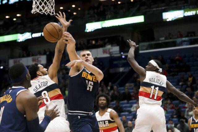 ; Denver Nuggets center Nikola Jokic (15) passes as he is defended by New Orleans Pelicans center Jahlil Okafor (8) and guard Jrue Holiday (11) during the second quarter at the Smoothie King Center.
