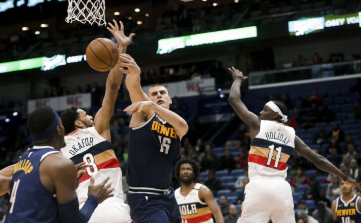 ; Denver Nuggets center Nikola Jokic (15) passes as he is defended by New Orleans Pelicans center Jahlil Okafor (8) and guard Jrue Holiday (11) during the second quarter at the Smoothie King Center.