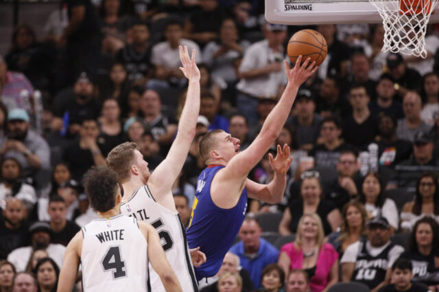 Denver Nuggets center Nikola Jokic (15) shoots the ball past San Antonio Spurs center Jakob Poeltl (left) in game four of the first round of the 2019 NBA Playoffs at AT&T Center.