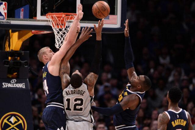 Denver Nuggets forward Mason Plumlee (24) and forward Paul Millsap (4) defend on San Antonio Spurs center LaMarcus Aldridge (12) in the first half in game seven of the first round of the 2019 NBA Playoffs at the Pepsi Center.