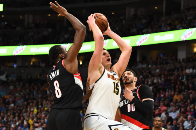 Denver Nuggets center Nikola Jokic (15) drives past Portland Trail Blazers forward Al-Farouq Aminu (8) and center Enes Kanter (00) in the third quarter in game five of the second round of the 2019 NBA Playoffs at Pepsi Center.