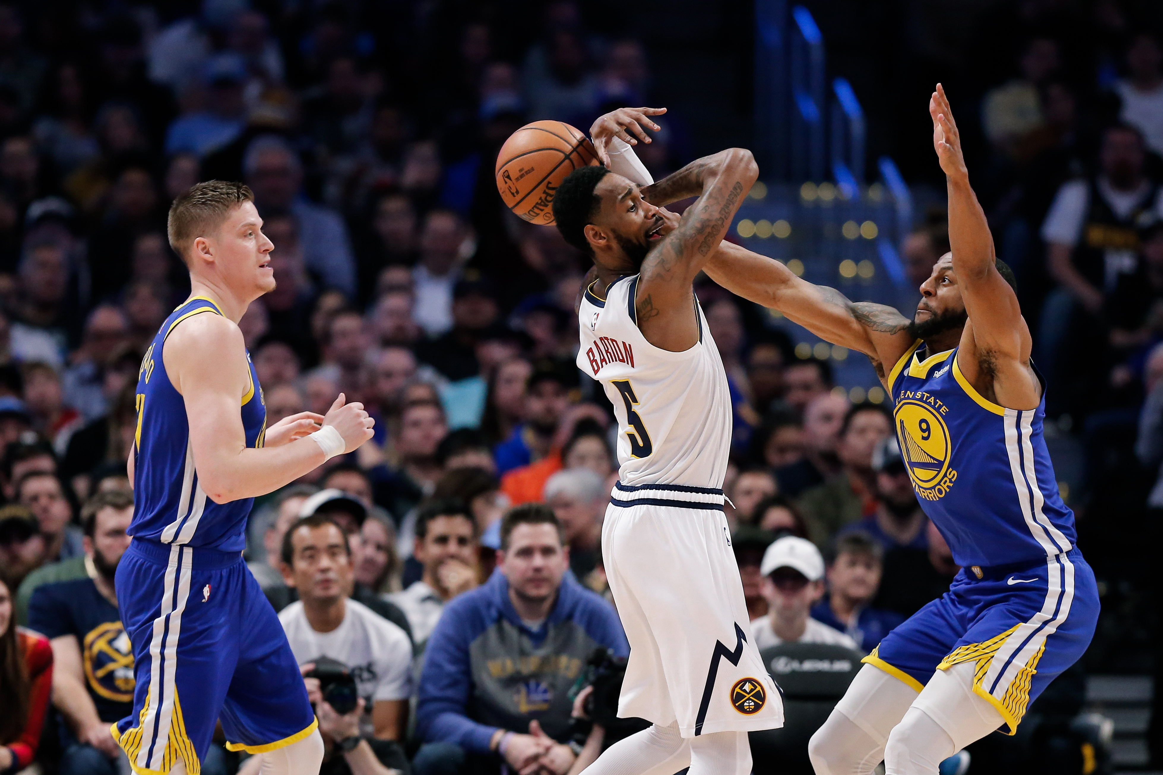 Golden State Warriors guard Andre Iguodala (9) knocks the ball away from Denver Nuggets guard Will Barton (5) as forward Jonas Jerebko (left) looks on in the fourth quarter at the Pepsi Center.