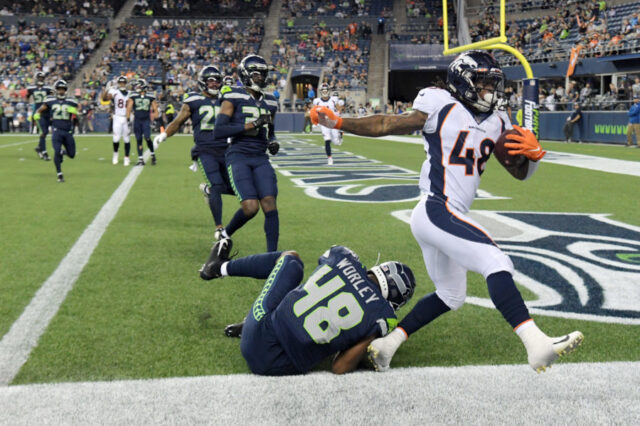 Denver Broncos running back Devontae Jackson (right) scores on a four-yard touchdown pass against Seattle Seahawks linebacker Chris Worley (48) in the fourth quarter at CenturyLink Field. The Seahawks won 22-14.