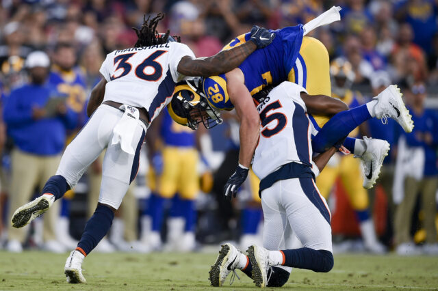 Los Angeles Rams tight end Johnny Mundt (82) is tackled by Denver Broncos safety Dymonte Thomas (35) and Denver Broncos safety Trey Marshall (36) after a catch during the first half at Los Angeles Memorial Coliseum.