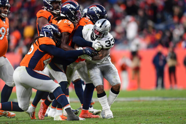 Denver Broncos inside linebacker Todd Davis (51) and cornerback Isaac Yiadom (26) and linebacker A.J. Johnson (45) tackle Oakland Raiders running back DeAndre Washington (33) in the second half at Empower Field at Mile High.
