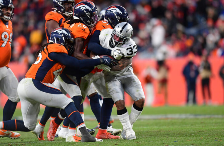 Denver Broncos inside linebacker Todd Davis (51) and cornerback Isaac Yiadom (26) and linebacker A.J. Johnson (45) tackle Oakland Raiders running back DeAndre Washington (33) in the second half at Empower Field at Mile High.