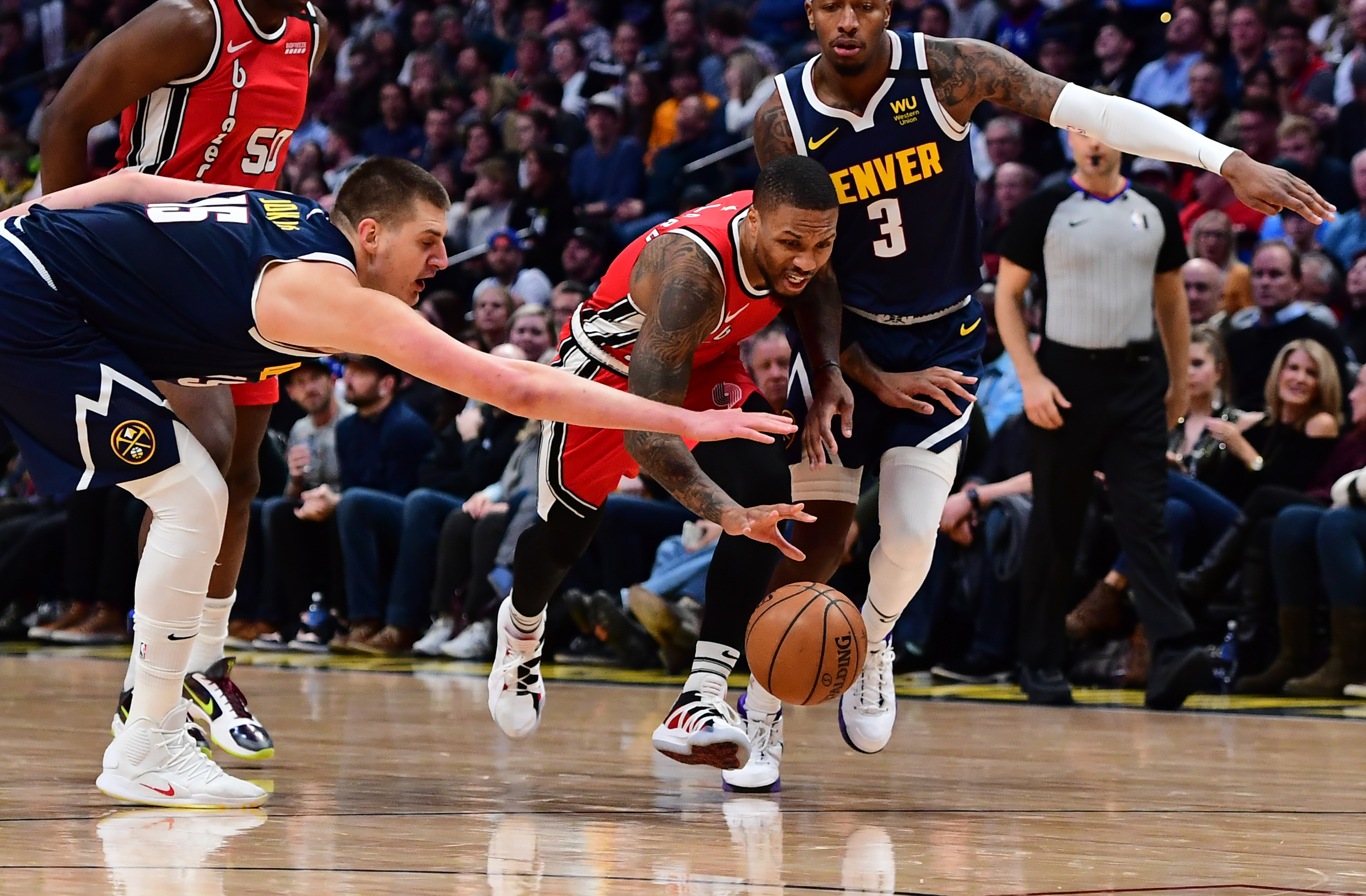 Nuggets center Nikola Jokic (15) reaches in on Portland Trail Blazers guard Damian Lillard (0) as forward Torrey Craig (3) chases from behind in the second half at Pepsi Center. Mandatory Credit: Ron Chenoy-USA TODAY Sports