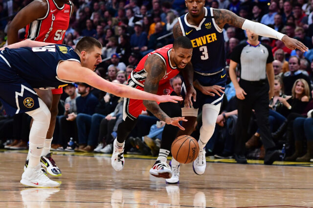 Nuggets center Nikola Jokic (15) reaches in on Portland Trail Blazers guard Damian Lillard (0) as forward Torrey Craig (3) chases from behind in the second half at Pepsi Center. Mandatory Credit: Ron Chenoy-USA TODAY Sports