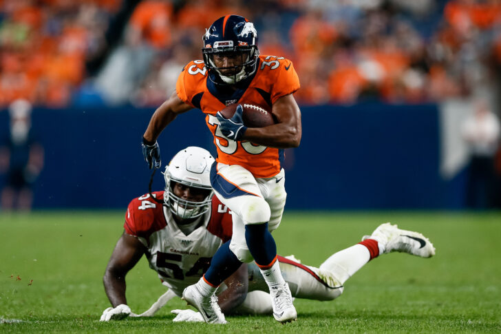 Denver Broncos running back Khalfani Muhammad (33) runs through the tackle of Arizona Cardinals linebacker Vontarrius Dora (54) in the fourth quarter at Broncos Stadium at Mile High.