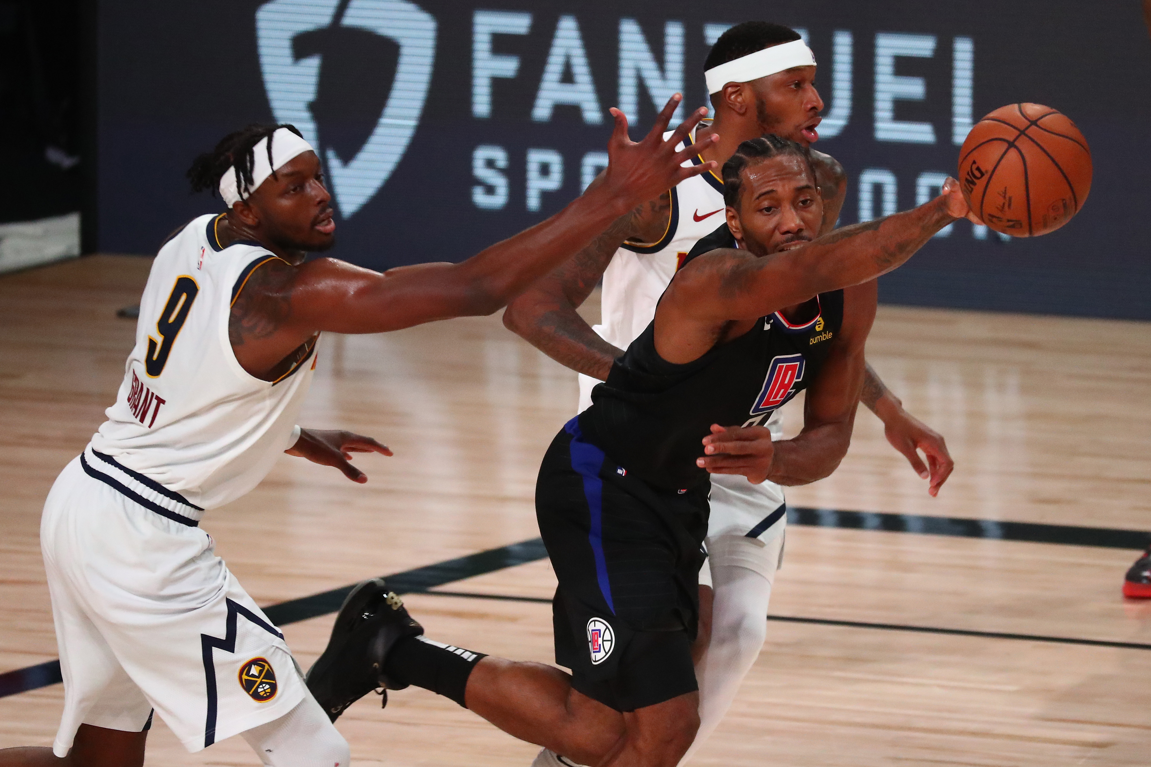 LA Clippers forward Kawhi Leonard (middle) is fouled by Denver Nuggets forward Torrey Craig (right) as he passes the ball against Denver forward Jerami Grant (9) during the first half of game two in the second round of the 2020 NBA Playoffs at AdventHealth Arena.