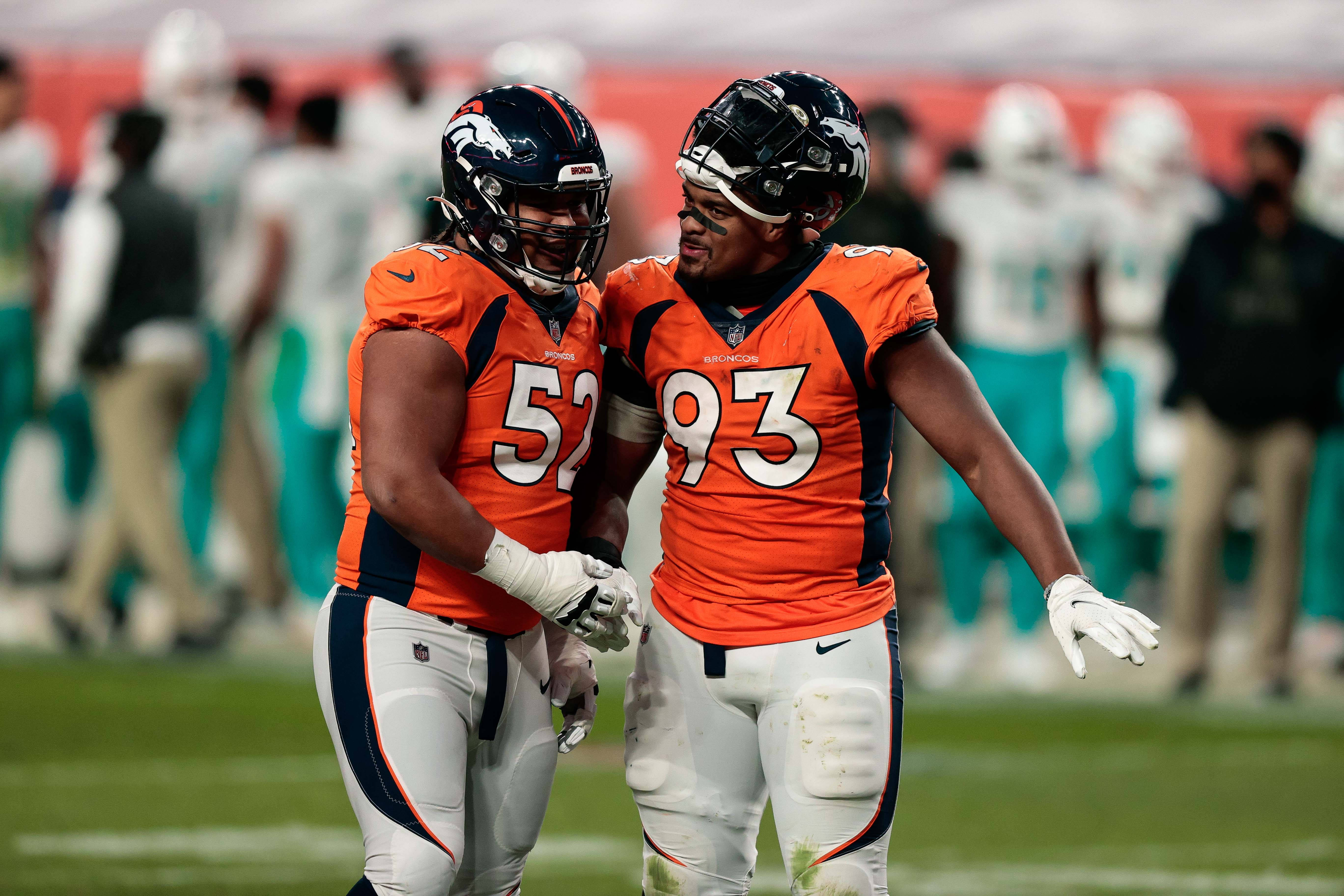 Denver Broncos guard Netane Muti (52) and defensive end Dre'Mont Jones (93) talk during a timeout in the fourth quarter against the Miami Dolphins at Empower Field at Mile High.