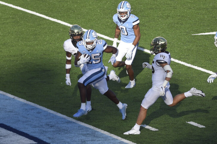 North Carolina Tar Heels running back Javonte Williams (25) scores a touchdown as Wake Forest Demon Deacons defensive backs Caelen Carson (29) and Nick Andersen (45) defend in the fourth quarter at Kenan Memorial Stadium