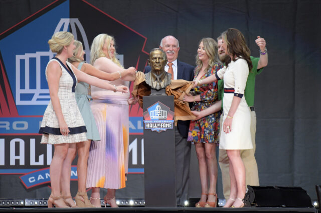Members of the Bowlen family and presenter Steve Antonopulos unveil the bust of the late Pat Bowlen during the Pro Football Hall of Fame Enshrinement at Tom Benson Hall of Fame Stadium.