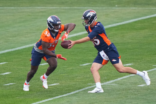 Denver Broncos quarterback Case Cookus (15) hands the ball off to running back Javonte Williams (33) during rookie minicamp at the UCHealth Training Center.
