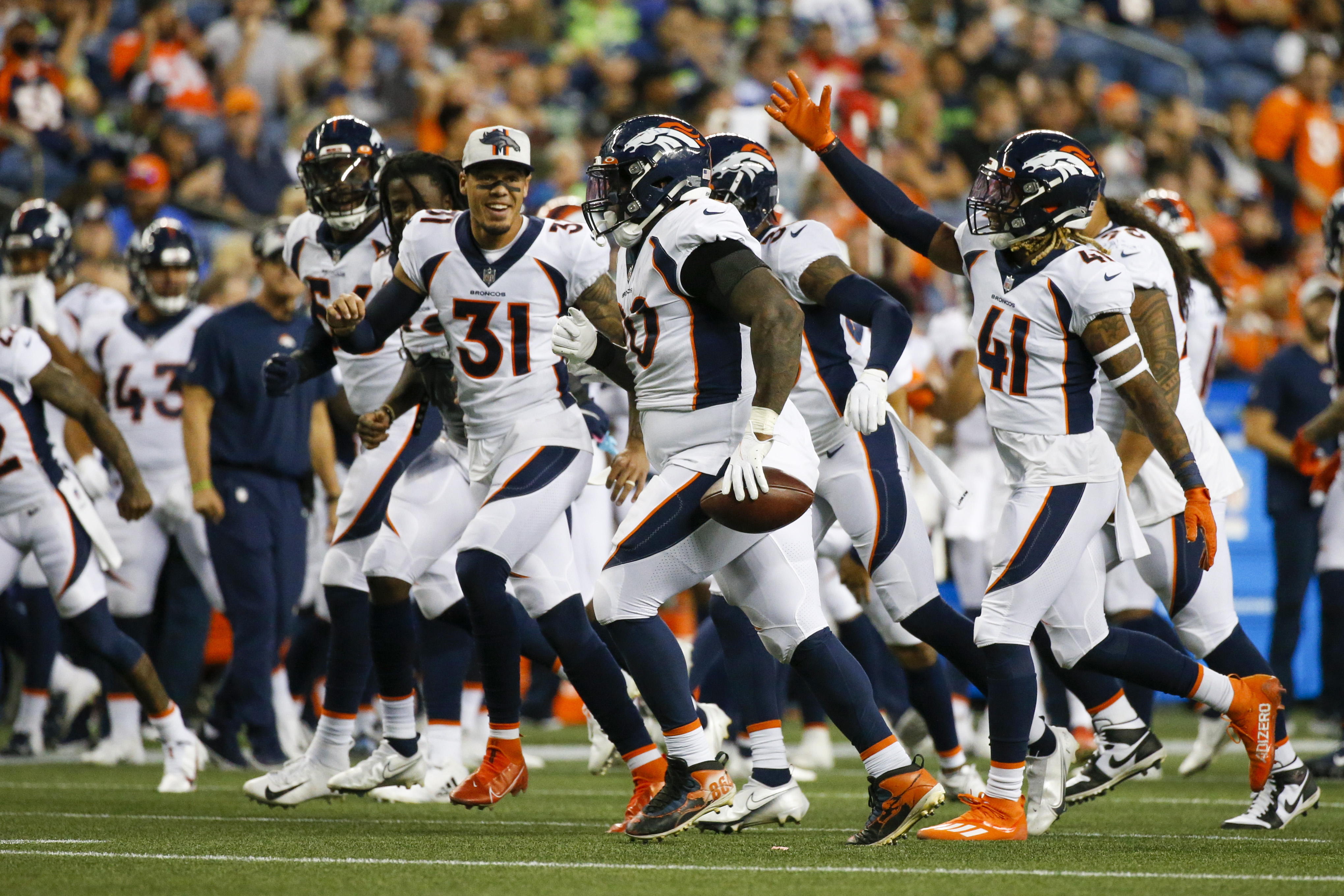 Denver Broncos defensive end DeShawn Williams (90) celebrates with teammates, including safety Jamar Johnson (41) after recovering a fumble against the Seattle Seahawks during the second quarter at Lumen Field.
