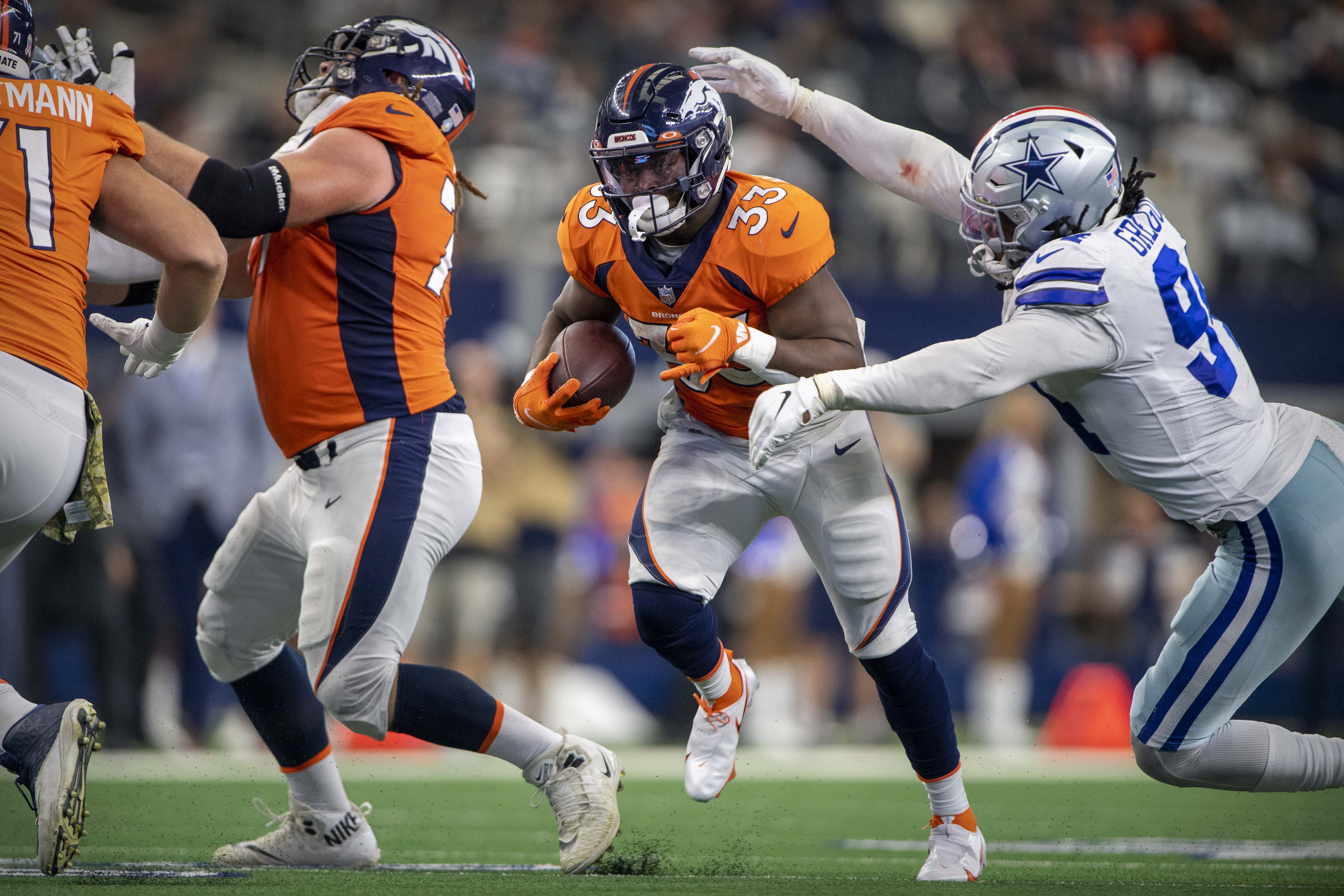 Denver Broncos running back Javonte Williams (33) tries to elude Dallas Cowboys defensive end Randy Gregory (94) during the second half at AT&T Stadium.