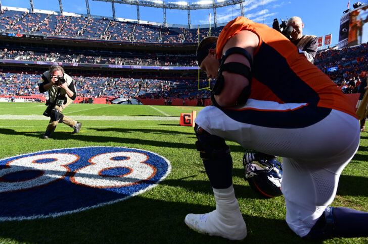 Denver Broncos offensive tackle Garett Bolles (72) kneels at the turf emblem for American football player Demaryius Thomas before the game against the Detroit Lions at Empower Field at Mile High.