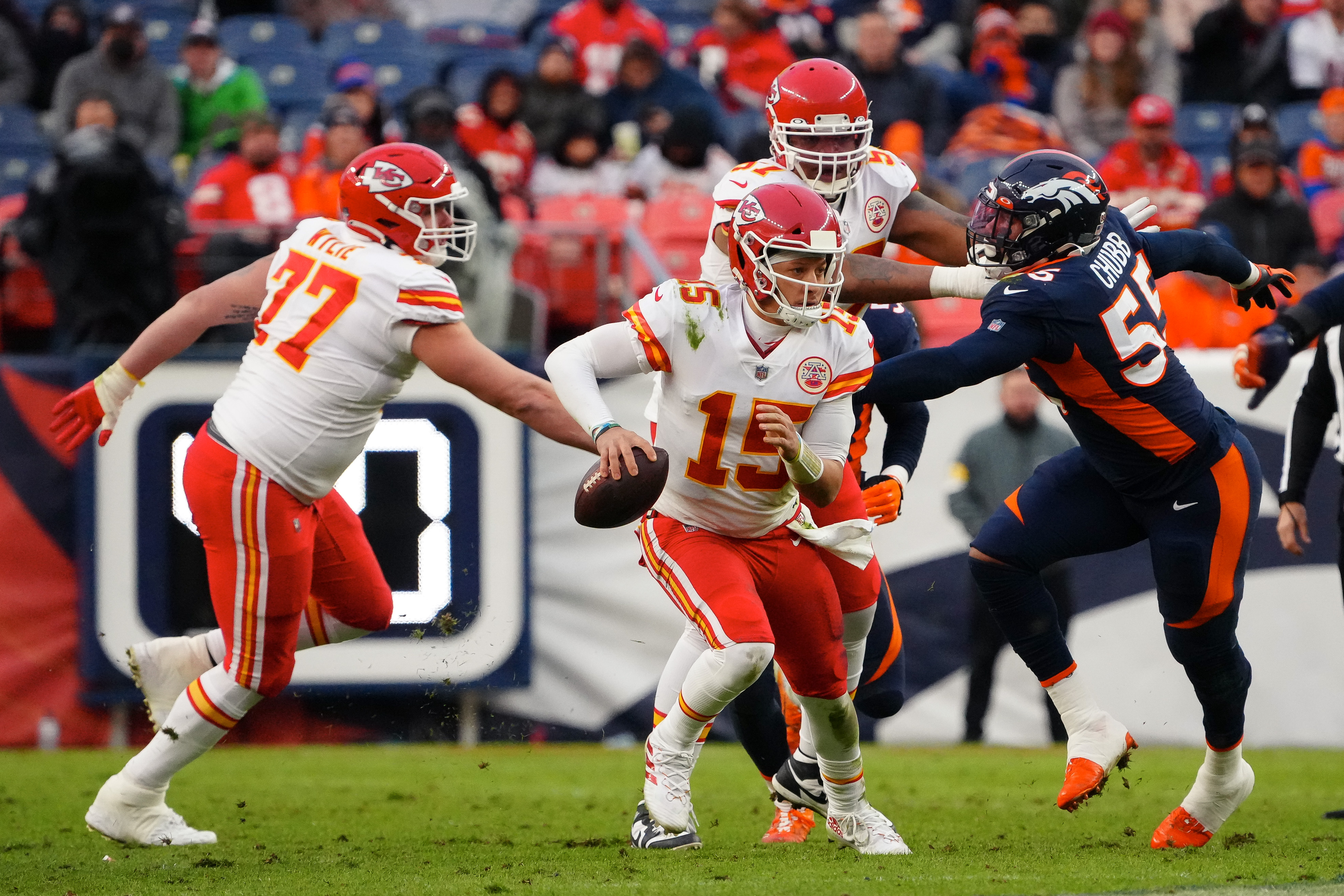 Kansas City Chiefs quarterback Patrick Mahomes (15) scrambles with the ball ahead of guard Andrew Wylie (77) as offensive tackle Orlando Brown (57) defends against Denver Broncos outside linebacker Bradley Chubb (55) in the third quarter at Empower Field at Mile High.