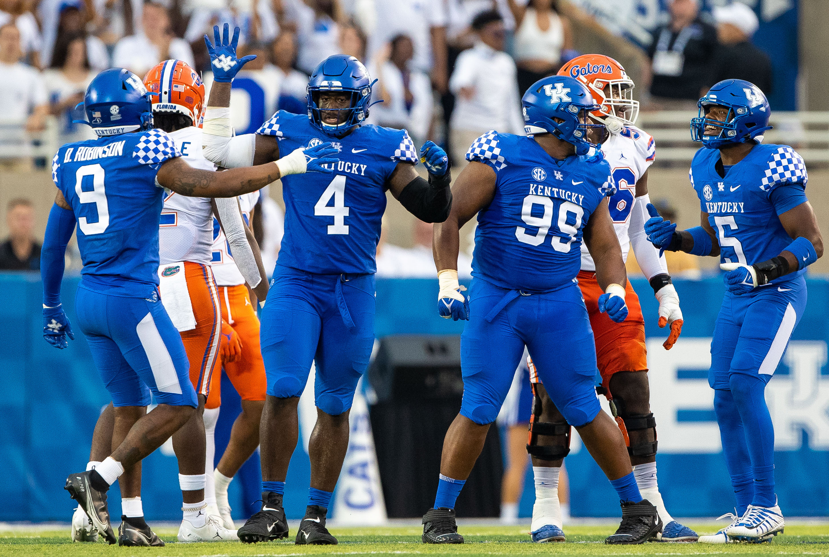 Kentucky Wildcats defensive back Davonte Robinson (9), defensive end Josh Paschal (4), defensive lineman Josaih Hayes (99) and linebacker DeAndre Square (5) celebrate a stop during the second quarter against the Florida Gators at Kroger Field.