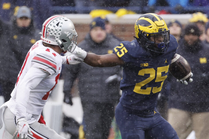 Michigan Wolverines running back Hassan Haskins (25) stiff arms Ohio State Buckeyes safety Bryson Shaw (17) in the second half at Michigan Stadium.