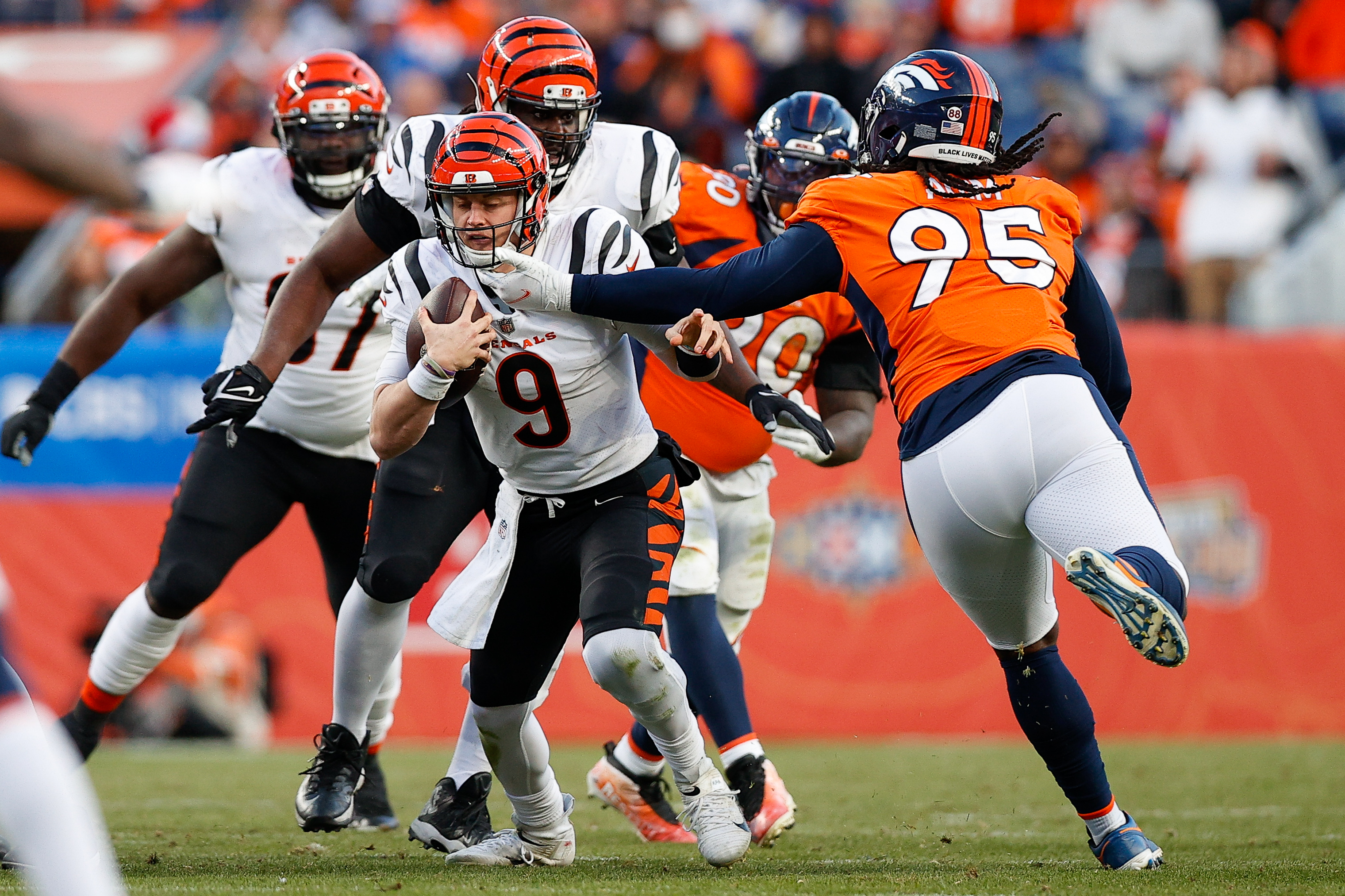 Cincinnati Bengals quarterback Joe Burrow (9) is face masked by Denver Broncos defensive tackle McTelvin Agim (95) in the third quarter at Empower Field at Mile High.