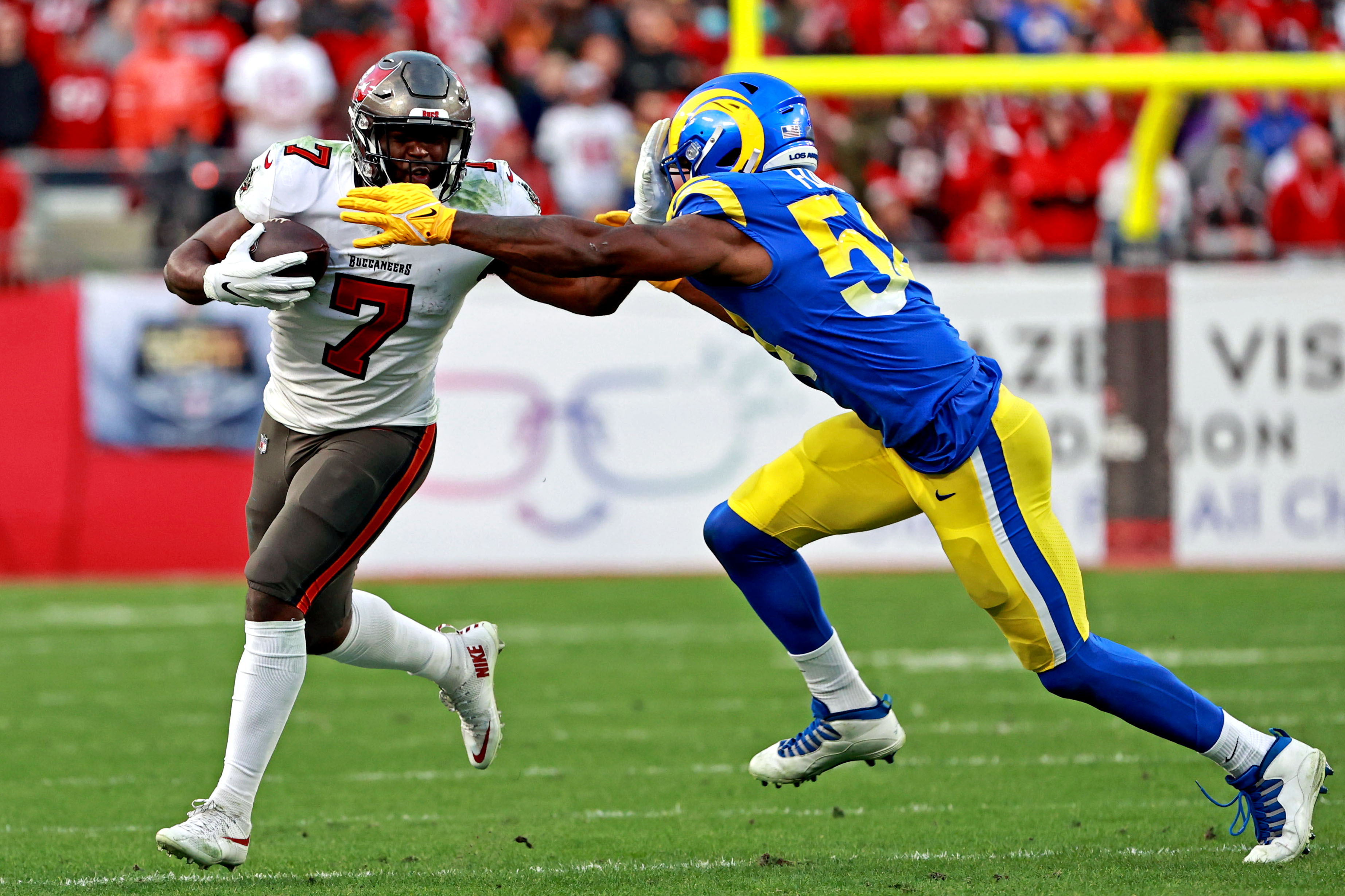 Tampa Bay Buccaneers running back Leonard Fournette (7) runs the ball against Los Angeles Rams outside linebacker Justin Hollins (58) during the second half in a NFC Divisional playoff football game at Raymond James Stadium. 