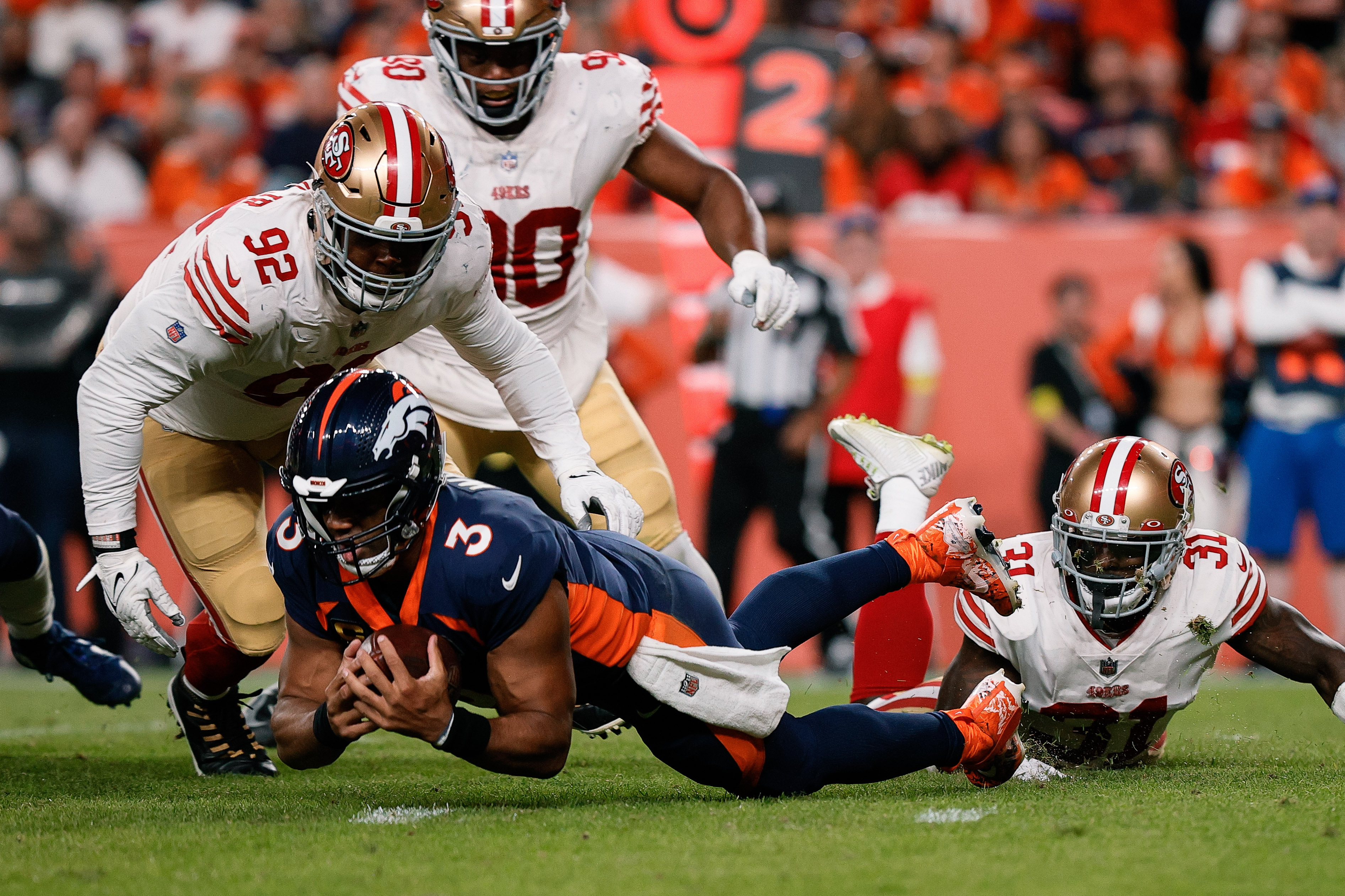Denver Broncos quarterback Russell Wilson (3) recovers a fumble ahead of San Francisco 49ers defensive end Kerry Hyder Jr. (92) and defensive tackle Kevin Givens (90) and safety Tashaun Gipson Sr. (31) in the third quarter at Empower Field at Mile High.