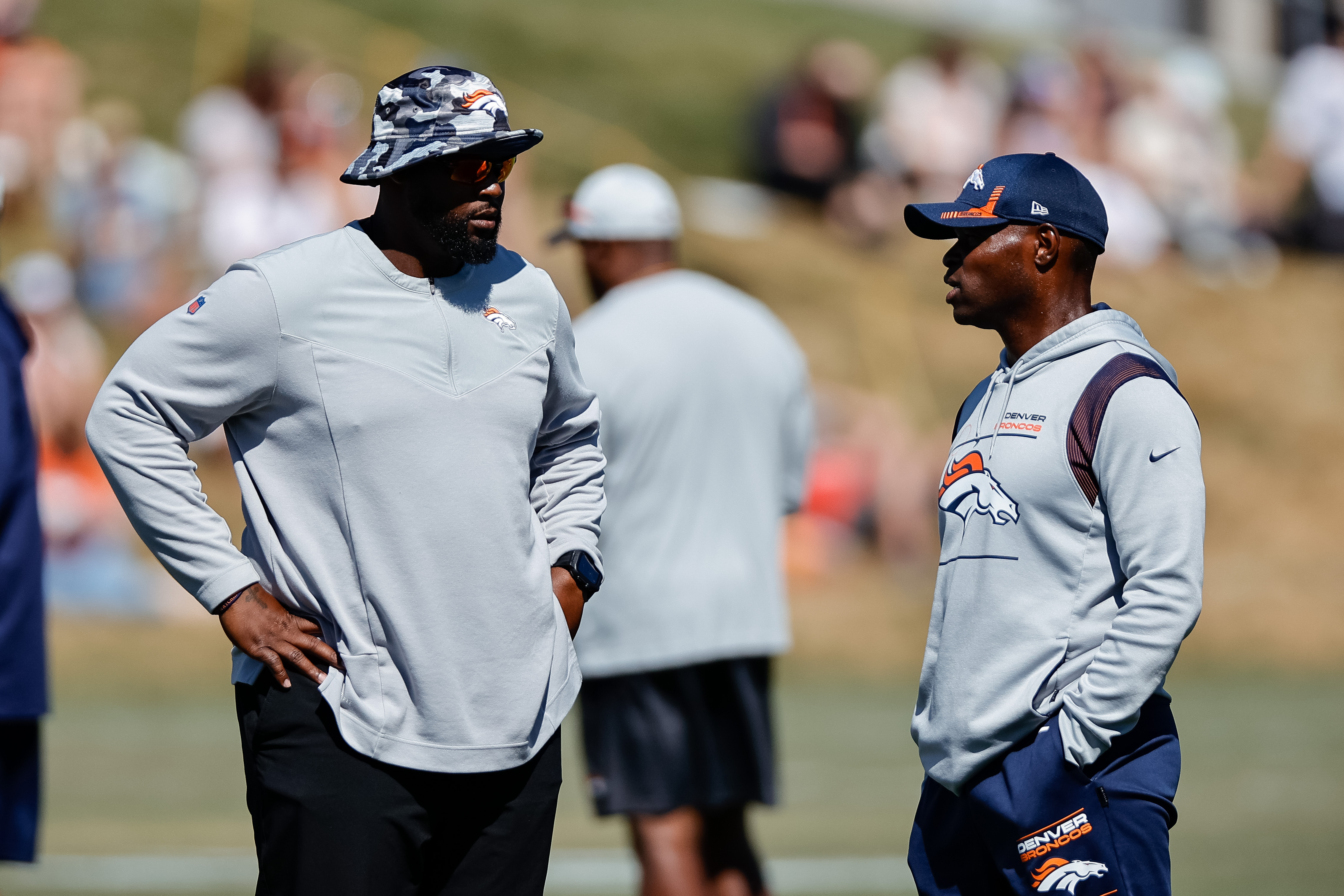 Denver Broncos defensive line coach Marcus Dixon (L) talks with defensive coordinator Ejiro Evero (R) during training camp at the UCHealth Training Center.