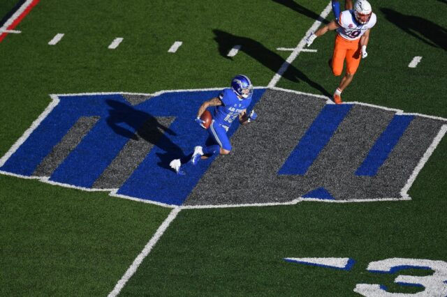 Mountain West logo on Air Force's field, a player runs with the ball and another chases.