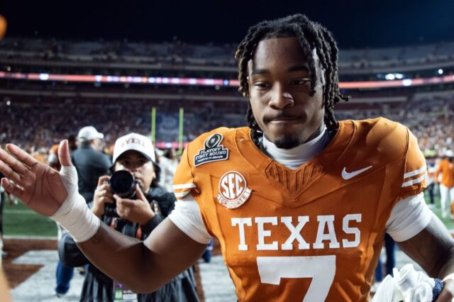Jahdae Barron gives a teammate a high five. A photographer follows him.