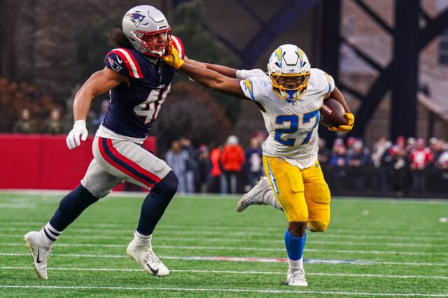 JK Dobbins stiff arms a Patriots player.