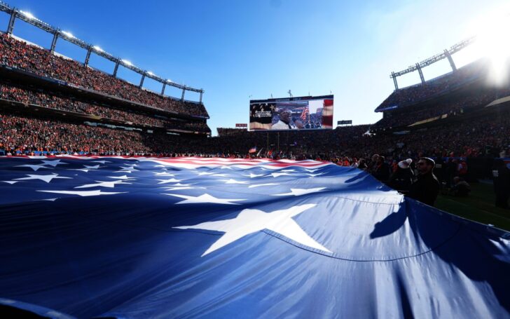 Empower Field at Mile High Stadium. A giant American flag is in the foreground.